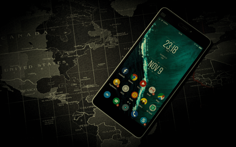 A smartphone displaying the current date and time resting on a dark world map, suggesting the use of mobile devices for global connectivity and information access.