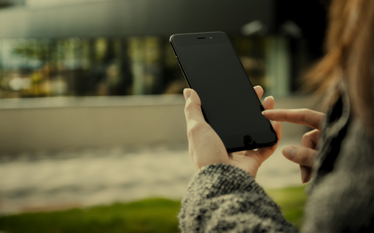 A person's hands holding a smartphone in an outdoor environment, suggesting the use of mobile devices to access information or communicate while in natural settings.