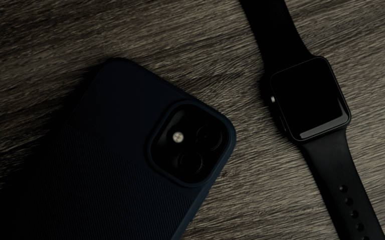 A close-up view of a smartphone and smartwatch in a dark setting, showcasing the integration of mobile technology and wearable devices.