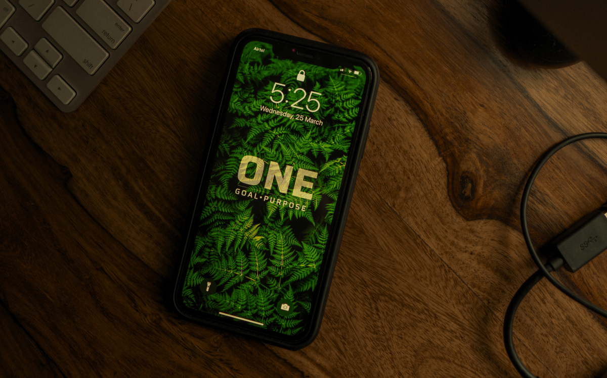 A smartphone screen displaying the time and date against a lush, nature-inspired background, suggesting the integration of technology with environmental aesthetics.