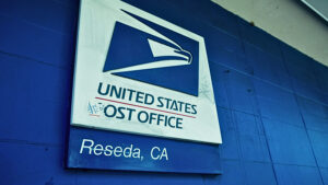 Close-up of a United States Post Office sign mounted on a blue wall in Reseda, California.